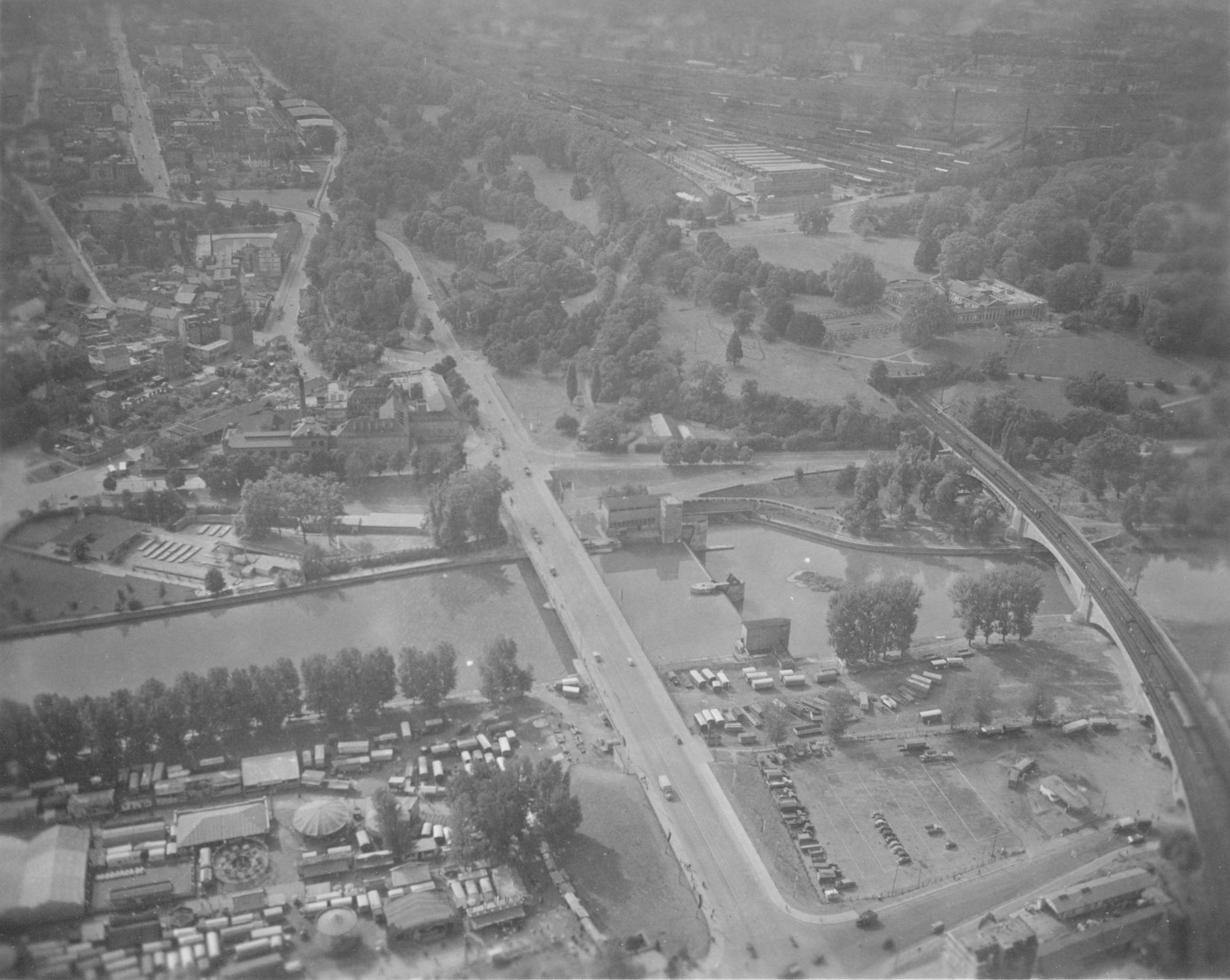 Luftaufnahme vom Neckar mit Stauwehr und Kraftwerk, König-Karls-Brücke und Rosenstein - Eisenbahnbrücke. Im Hintergrund Rosensteinpark mit Schloß, Cannstatter Wasen.